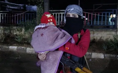 امرأة تحمل طفلتها وتشارك في حماية المنطقة ضمن النفير العام