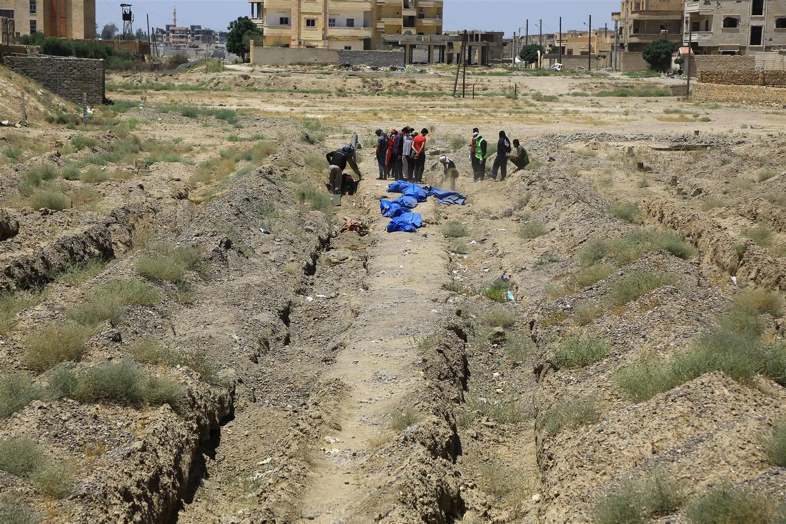 Mass graves of thousands of unidentified corpses, teams working to pull them out