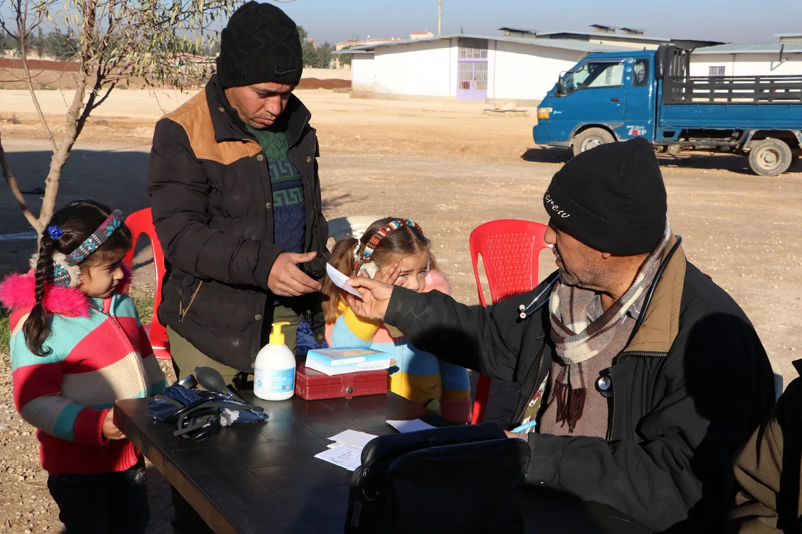 Un médico trata a sus pacientes bajo la luz del sol por el cerco impuesto por el gobierno de Damasco