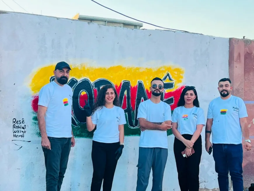 Jóvenes de Kobanê pintan el nombre de la ciudad en un mural artístico