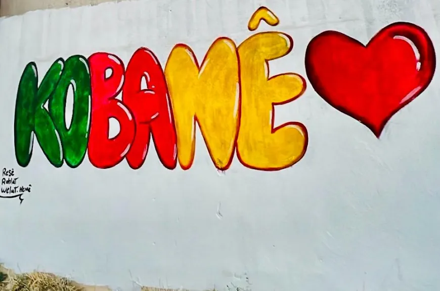 Jóvenes de Kobanê pintan el nombre de la ciudad en un mural artístico
