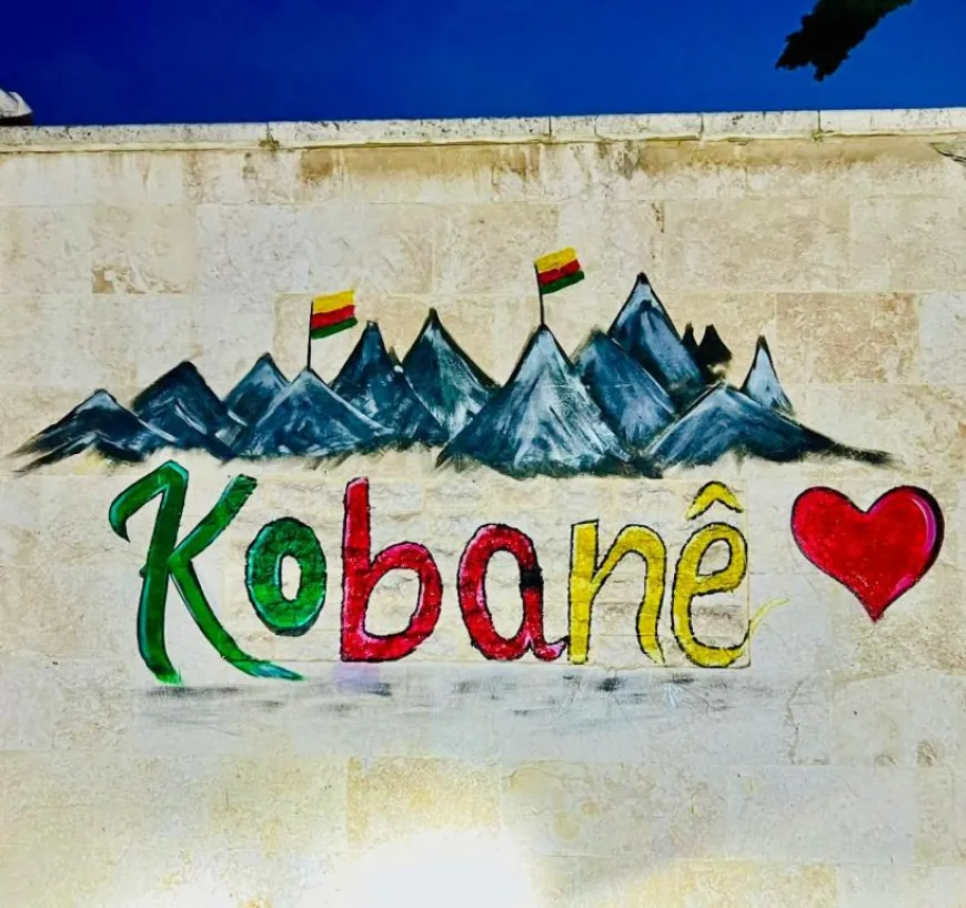 Jóvenes de Kobanê pintan el nombre de la ciudad en un mural artístico